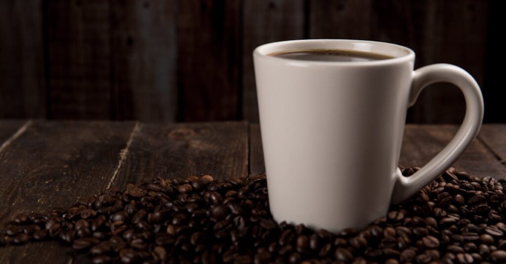 A rustic ceramic mug filled with hot coffee, surrounded by coffee beans on a wooden table.